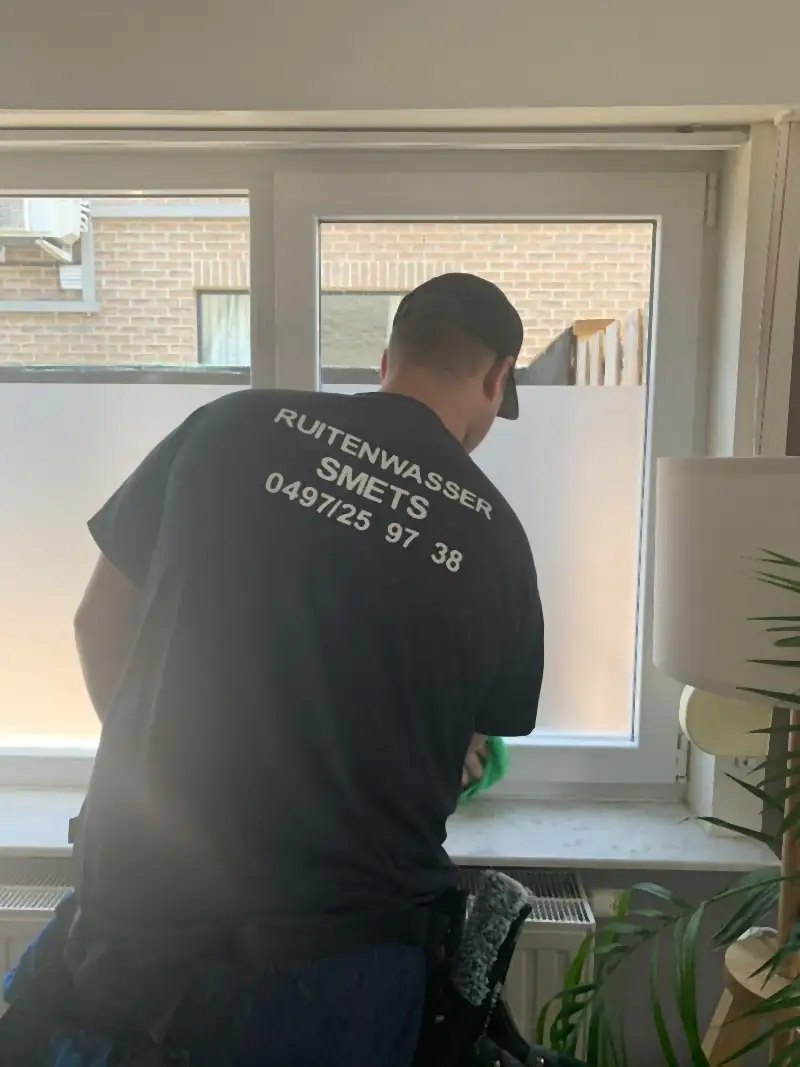 Glazenwasser wast een groot raam aan de binnenkant van een woonkamer